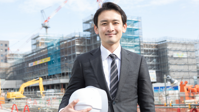 ヘルメットを片手に笑顔の建設現場の責任者