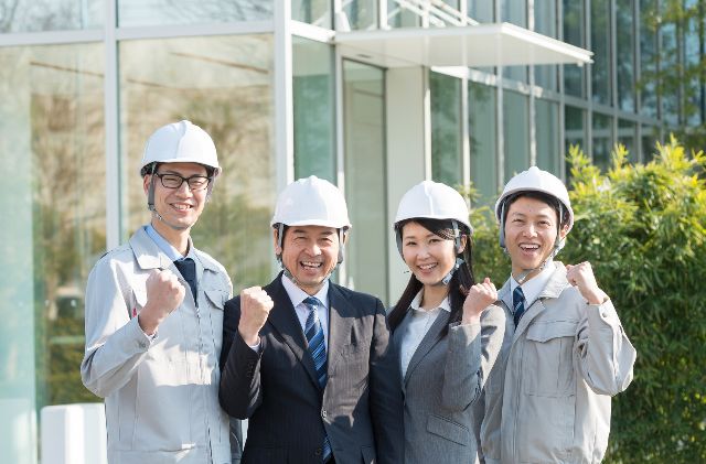 会社の前でガッツポーズをする建設業者たち