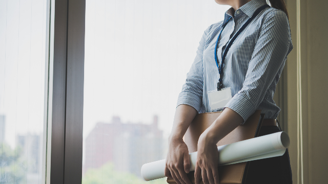 書類を抱えてたたずむ建設会社の女性